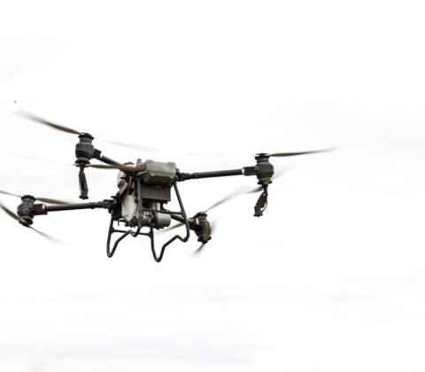 A commercial drone inspecting a power line in a utility setting, showcasing advanced technology and safety measures.